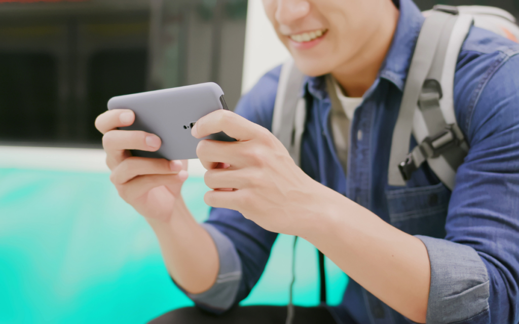 A man looking at his phone examining the app store product page of Japan vs Korea