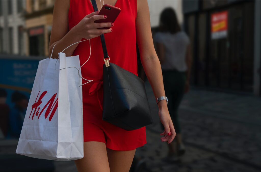 A woman shopping from H&M and using her phone